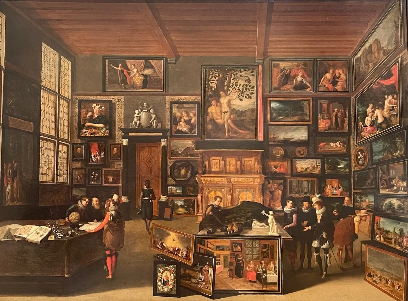 Intérieur d'une galerie aux murs couverts de tableaux ; des visiteurs en habits sombres et, au centre, un jeune garçon noir.