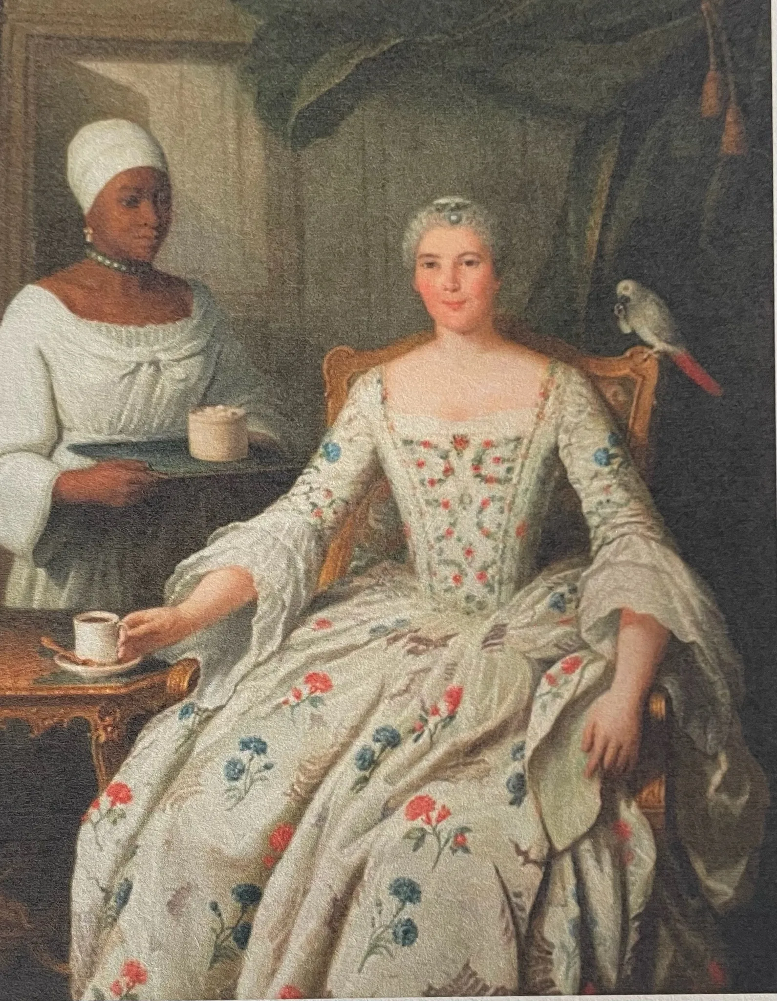 Femme en robe richement ornée, assise ; à ses côtés, une femme noire en vêtements clairs lui présente un objet.