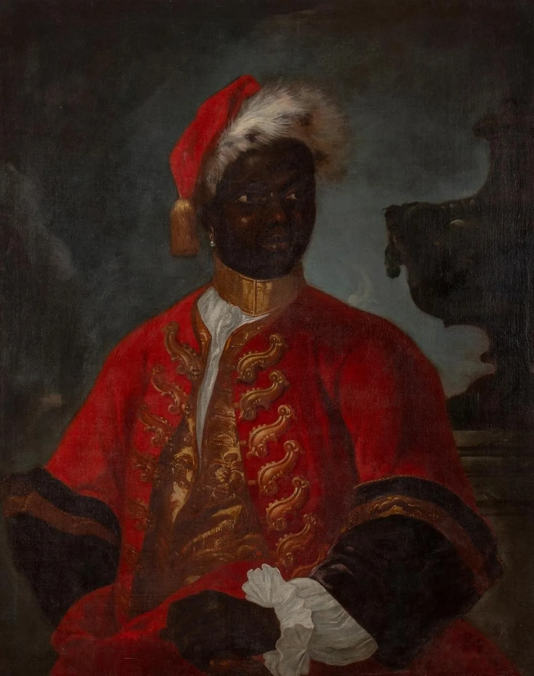 Portrait d'un homme noir en livrée rouge richement brodée, portant un collier métallique.