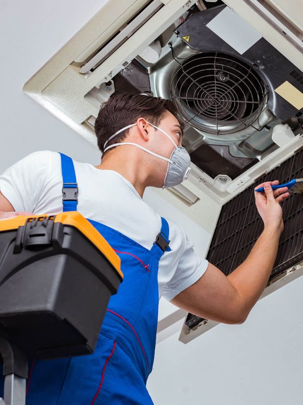 Domiraqo AC technician servicing a split unit in a Lahore apartment
